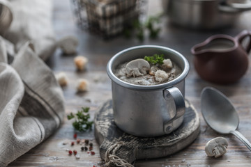 Hot mushroom cream soup of champignons with steam in a metal mug