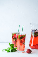 Homemade fresh strawberry lemonade with basil leaves on a light background copy space.