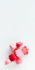 Beauty care. Sliced pink, red lipstick samples on white background.