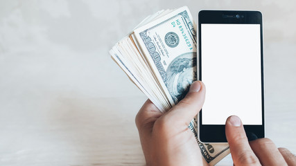 Online banking mobile app. Smartphone, dollars. Man hands with cash money.