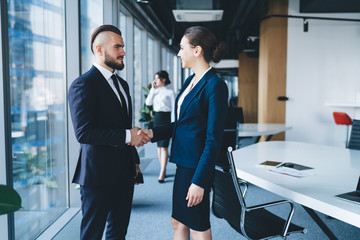 Friendly coworkers shaking hands after deal in office