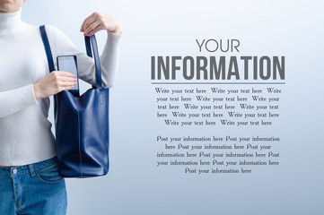Woman put mobile phone into blue bag on gray light background, space for text