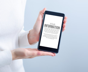 Woman holding mobile phone on gray light background, space for text