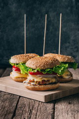 Fresh tasty grilled beef burgers with cheese wood background.