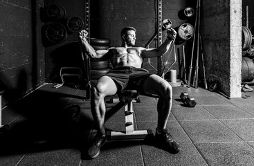Fototapeta na wymiar Young strong focused fit muscular man chest bench press stretching cross workout training in the gym with rubber for strength and good looking of muscles dark image real people selective focus 