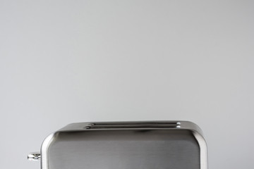 Old Fashioned stainless steel retro toaster on the gray background and white table.