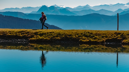 Beautiful alpine view with hiker silhouettes and reflections in a lake at Leogang, Tyrol, Austria