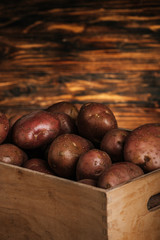 Obraz premium close up view of fresh ripe potatoes in box on wooden background