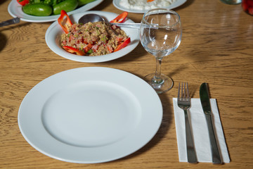 Table setting on wooden table . Dinner place setting. A white plate with silver fork and Wine glasses isolated on wood table. top view . Set of a dish with spoon, fork and knife on wooden table.