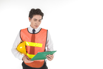 Portrait of smart young asian engineer businessman wearing white shirt and safety vest and holding helmet and looking to green paper clipboard on isolated white background and copy space.