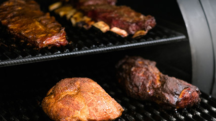 Grill restaurant kitchen. Closeup of poultry, beef and pork meat, ribs cooked in BBQ smoker.