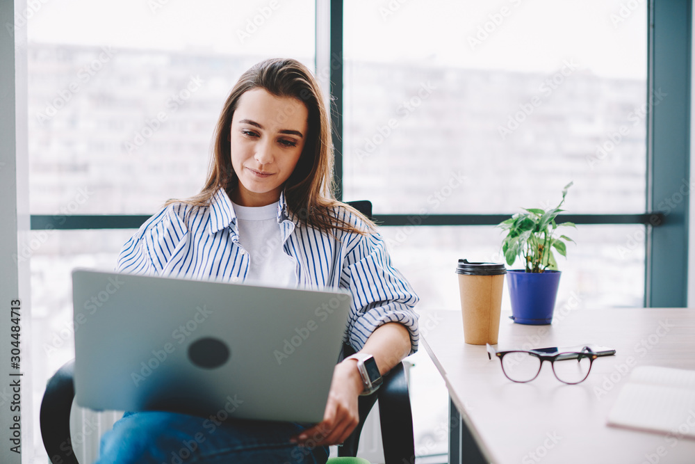 Wall mural serious woman watching video on laptop computer analyzing information for review sitting at desktop,