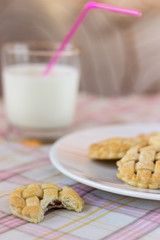 Tasty homemade jam cookies and glass of milk on pink tablecloth. Copy, empty space for text