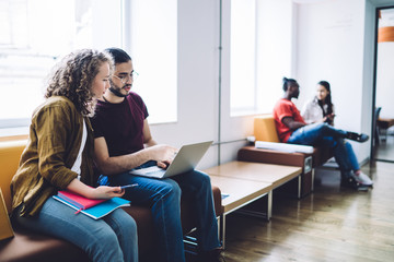 Young students working on laptop in hall