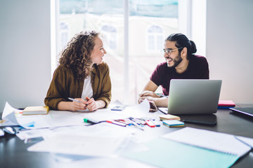 Laughing coworking man and woman with laptop