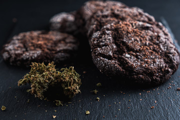 three chocolate chip cookies with marijuana lie on a slate dish