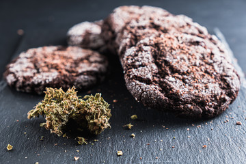 three chocolate chip cookies with marijuana lie on a slate dish