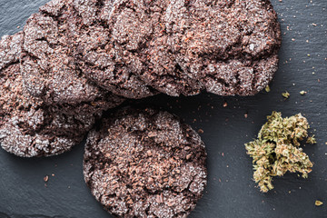 chocolate chip cookies with marijuana, sprinkled with chocolate chips and cannabis, are on a slate dish.