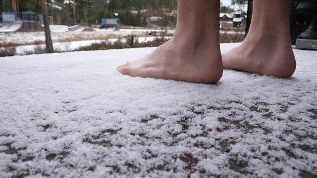 Man steps out barefoot on his porch in frigid ice and snow after a fresh snowfall - low angle close up