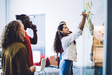 Smiling woman with group mates arranging notes on wall