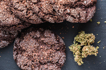 chocolate chip cookies with marijuana, sprinkled with chocolate chips and cannabis, are on a slate dish.