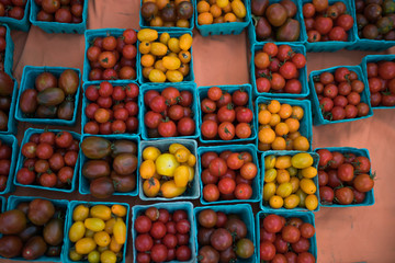 Pint baskets of organic red tomatoes on the counter at a farmer's market. Raw organic autumn farmers market box with raw fresh vegetables. Local produce at the summer farmers market in the city.