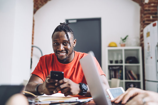 Cheerful Black Man With Smartphone At Desk