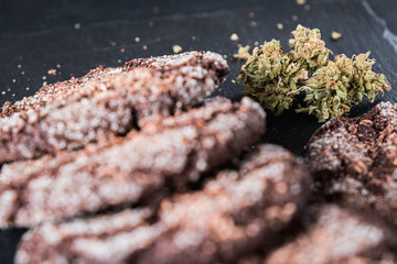 chocolate chip cookies with marijuana, sprinkled with chocolate chips and cannabis, are on a slate dish.