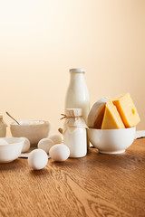 tasty organic dairy products and eggs on rustic wooden table isolated on beige