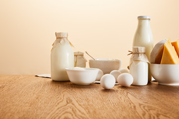 tasty organic dairy products and eggs on rustic wooden table isolated on beige