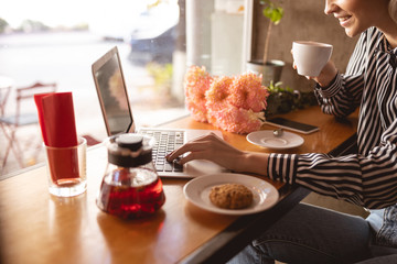 Cheerful woman working remotely from the cafe