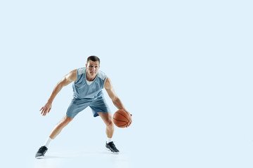 Fototapeta na wymiar Passioned for. Young caucasian basketball player of team in action, motion in jump isolated on blue background. Concept of sport, movement, energy and dynamic, healthy lifestyle. Training, practicing.