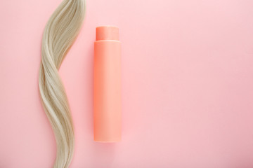 Shampoo for colored hair. Mockup bottle shampoo for blond. Pink bottle of cosmetic product and blonde hair on pink colored background. Space for design. Hairdresser service. Natural cosmetics concept
