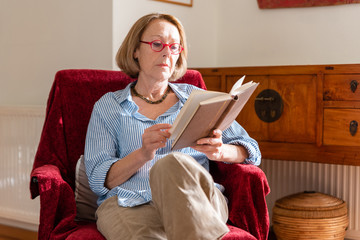Elegant mature woman is reading a book at home