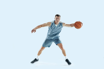 Fototapeta na wymiar Passioned for. Young caucasian basketball player of team in action, motion in jump isolated on blue background. Concept of sport, movement, energy and dynamic, healthy lifestyle. Training, practicing.