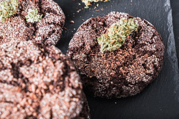 chocolate chip cookies with marijuana, sprinkled with chocolate chips and cannabis, are on a slate dish.