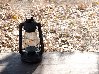 old oil lamp on a wooden bench in the autumn park