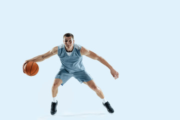Naklejka na ściany i meble Passioned for. Young caucasian basketball player of team in action, motion in jump isolated on blue background. Concept of sport, movement, energy and dynamic, healthy lifestyle. Training, practicing.