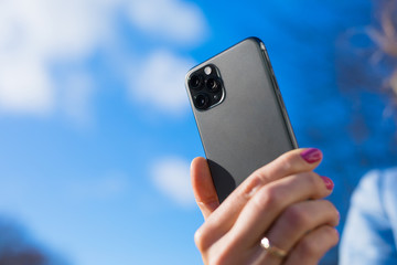Person holding modern smartphone with triple-lens camera