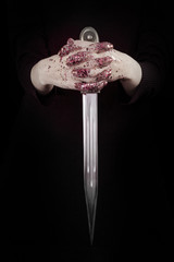 Beautiful woman hands with glitter holding a sword close up can be used as background