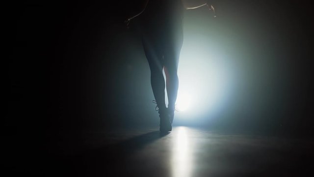 Girl walking beautifully in high heels..Dancer's legs in dark in smoky room of nightclub. Slow motion.