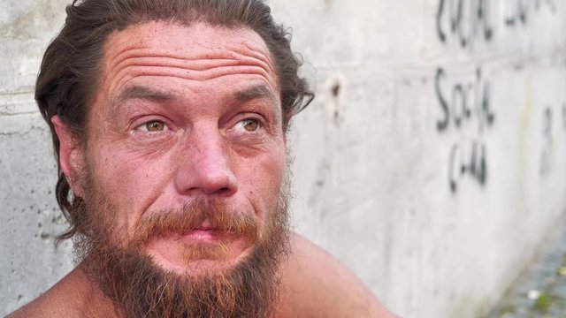 Destitute man looks at the camera and talks, real person with no fixed abode, homeless wanderer speaks on the camera