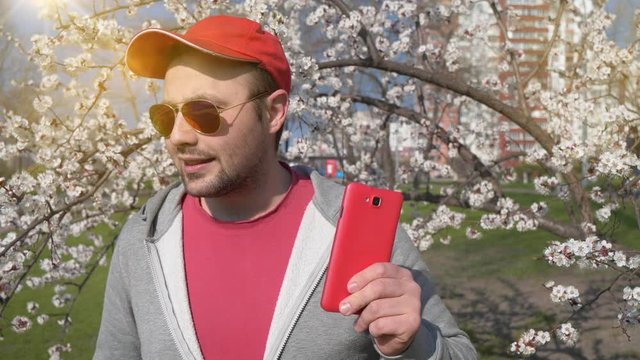 Funny man in red cap with red smartphone listens to music and dances