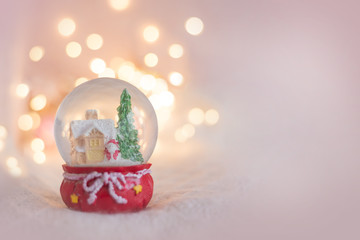 background for a Christmas card in light pink with a souvenir snow globe