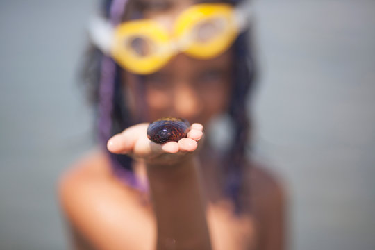 A little girl holds a sea cucumber on her hand, the girl’s face is out of focus