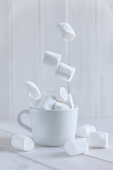 Fototapeta na wymiar Marshmallow falling into cup over white background