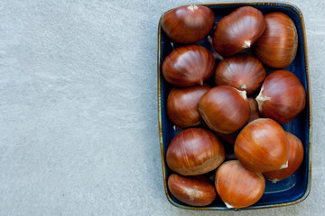 Obraz premium Edible chestnuts on a blue plate.