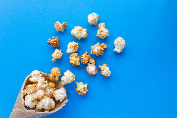 Ice cream cone with caramel popcorn on  the blue  background. Top view. Copy space.