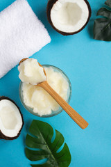 Spa composition. Coconut oil , white towel and coconut halves on  the blue background. Natural product. Top view. Copy space. Location vertical.