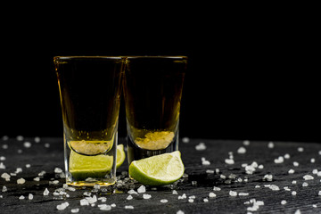 tequila is poured into two glasses and salt and lime